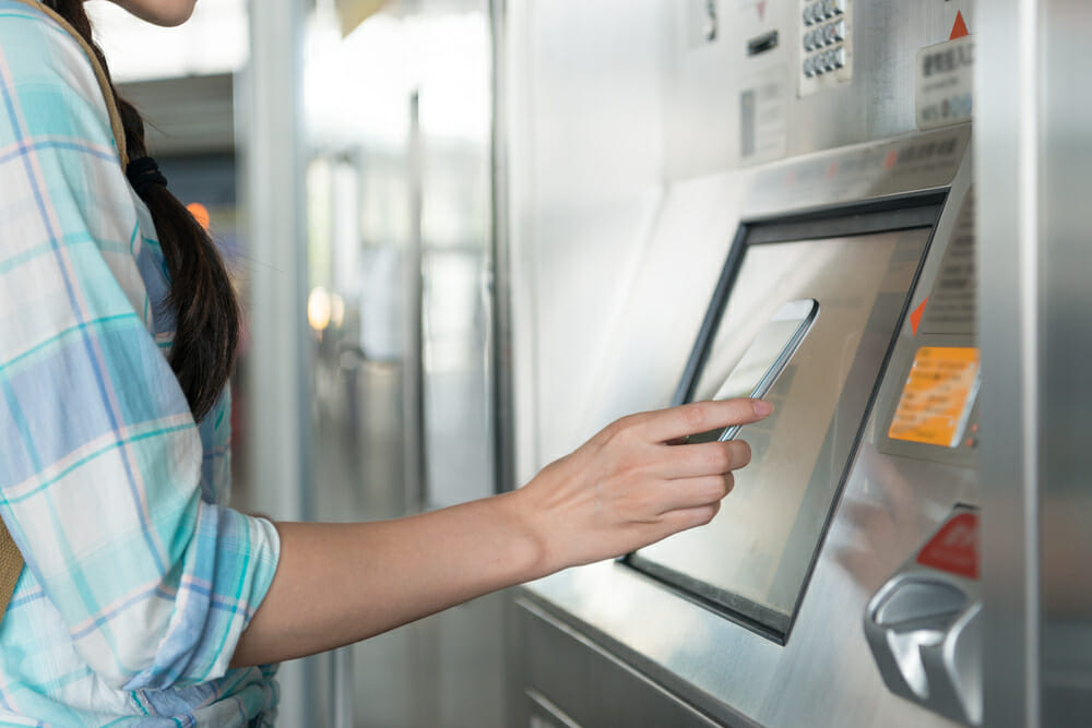 Woman scans her smartphone to pay for items at a self checkout | self-checkout grab-n-go kiosks, food and beverage carts